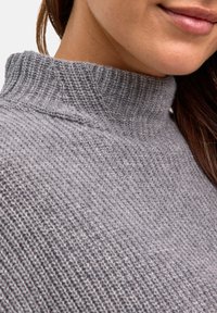 Maglione a collo alto grigio a maglia con un motivo testurizzato e colletto a coste; superficie liscia e vestibilità comoda, mostrato da vicino.