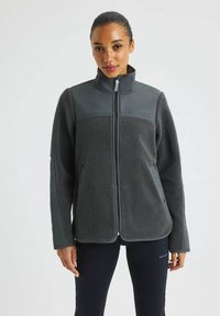 Tummanharmaa fleece-takki, jossa on sileä, erottuva hartiapaneeli, t�äysipitkä vetoketju ja sivutaskut. Karkeapintainen runko ja korkea kaulus.