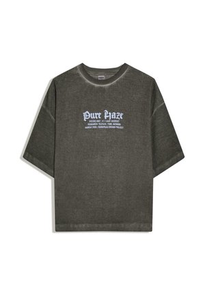 Dunkelgraues, geripptes T-Shirt mit kurzen Ärmeln und weißem Text "Pure Haze" sowie kleinerem Aufdruck, der auf ein europäisches Designprojekt zum Thema Textur und Erinnerung verweist.