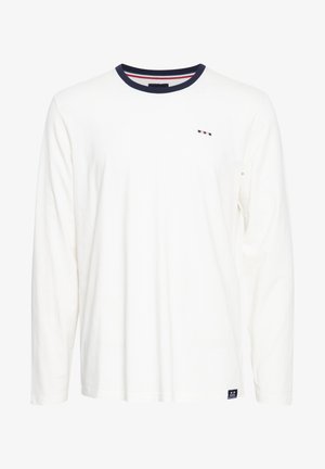 Valge pikakäigeline t-särk, mis on valmistatud puuvillast, omab mereväe sinist kaelust punaste ja valgete detailidega ning väikest logo rinnal.