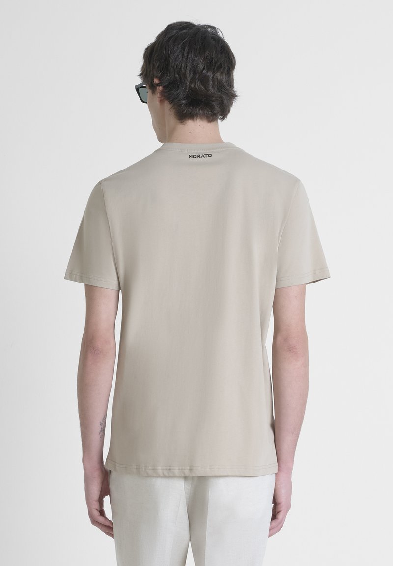 Camiseta de manga corta beige con corte recto, textura suave y detalles mínimos. Logo "Morato" impreso en la parte posterior del cuello.