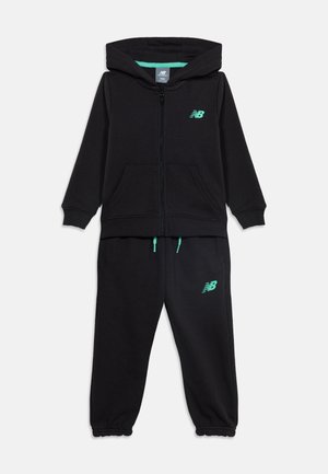 Survêtement noir New Balance pour enfants comprenant un sweat à capuche zippé et un pantalon de jogging à taille élastique, avec logos bleu sarcelle et détails à cordon.