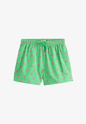 Short de bain vert avec motif flamant rose, taille élastique et cordon vert avec embouts roses.