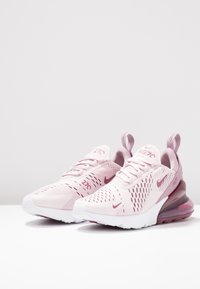 Helle rosa Sportschuhe aus atmungsaktivem Mesh mit strukturierten Akzenten und weißer Sohle. Sie verfügen über eine sichtbare Luftpolsterung in der Ferse und das Markenlogo.