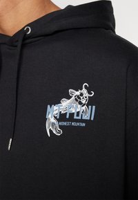 Hoodie noir avec impression graphique blanche et bleu clair d'un poisson et le texte "MT FUJI HAUTE MONTAGNE." Comprend une capuche à cordon de serrage et une texture douce.