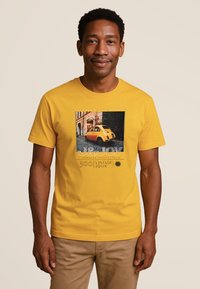 Gele katoenen T-shirt met een afbeelding van een vintage auto en tekst, met korte mouwen en een ronde hals.