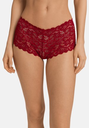 Des shorty en dentelle rouge présentent des bords à volants et des motifs floraux. Le tissu est transparent, offrant un aspect délicat et texturé.
