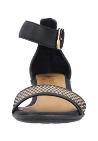 Offene Sandale mit einem schwarzen Lederknöchelriemen und einer goldenen Schnalle. Die Fußbett ist tanfarben, und der vordere Riemen hat ein schwarz-beiges Wabenmuster.