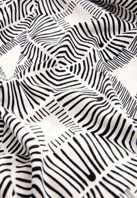 Zwart-witte stof met een golvend, lineair patroon met variërende dikte. Het materiaal oogt zacht en licht, wat de textuur benadrukt.