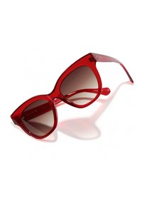 Piros műanyag macskaszem alakú napszemüveg, barna átmenetes lencsékkel és áttetsző szárakkal, enyhe logó részlettel.