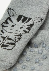 Calzini grigi con un design a strisce di tigre nera. La superficie presenta punti di grip testurizzati di un grigio chiaro per una migliore aderenza.