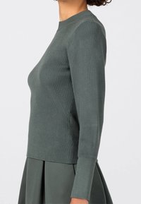 Ciemnozielony prążkowany sweter dzianinowy z okrągłym dekoltem i długimi rękawami, z detalami szwów po bokach oraz dopasowaną sylwetką.