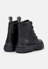Botas de cuero negro hasta el tobillo con punta redonda, ojales coloridos y suela de goma gruesa. Presenta tiradores con la marca en la parte trasera.