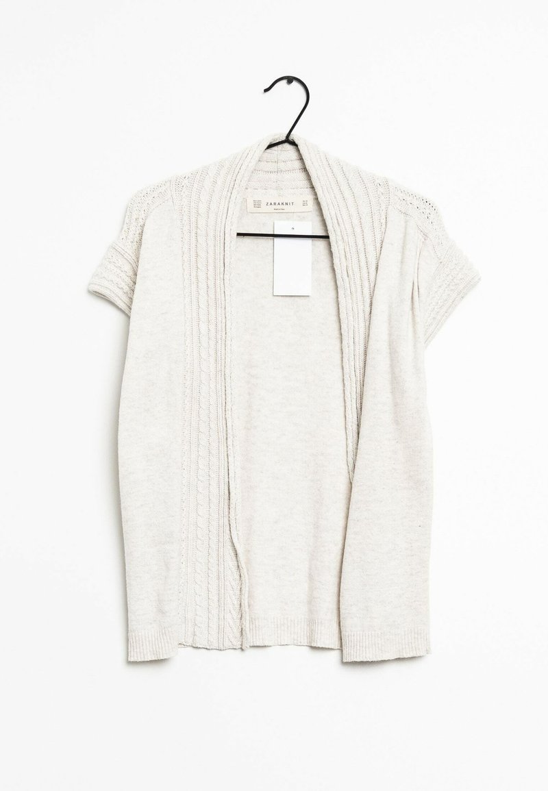 Helle beige Strickjacke aus Strickstoff, mit Kurzärmeln, gerippter Textur und einer Vorderöffnung mit dekorativen Nähdetails.