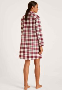 Camicia da notte a quadri con vestibilità rilassata, caratterizzata da quadrati rossi e bianchi. Realizzata in tessuto morbido, con maniche lunghe e spacchi laterali all'orlo.