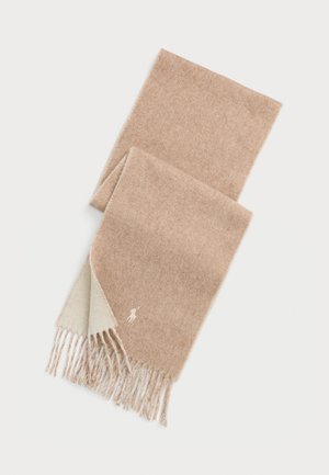Bufanda de lana beige con una textura suave, con bordes deshilachados y un logotipo bordado en un tono más claro. Diseño liso y rectangular.