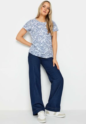 Lichtblauw T-shirt met korte mouwen en een luipaardprint, gecombineerd met hoge donkerblauwe wijde jeans en witte sneakers.