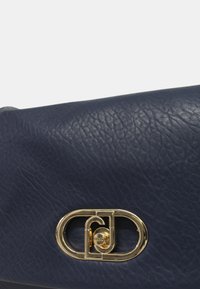 Borsa in pelle blu navy con finitura testurizzata, caratterizzata da una chiusura metallica dorata e una forma ovale arrotondata.