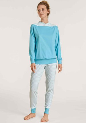 Light blue sweatshirt with a striped hood, paired with white pants featuring thin blue stripes. Soft fabric and a relaxed fit.