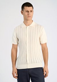 Kortärmad stickad cardigan i krämfärg, med kabelstickad textur, knapplist fram och en klassisk kragdesign.