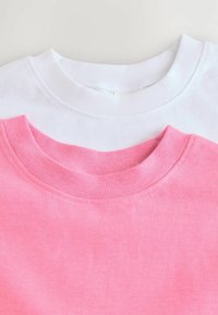 Due scollature di magliette sovrapposte, una rosa e una bianca. Entrambe hanno colli a costine e un tessuto morbido e liscio con una finitura in tinta unita.