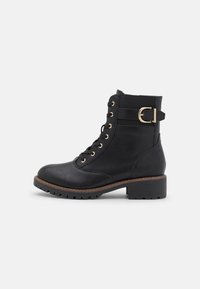 Botine negre din piele cu șireturi în față, cu accente din metal aurit, talpă din cauciuc și un toc masiv și confortabil. Prezintă o curea decorativă pe lateral.