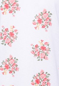 Tecido branco com padrões de aglomerados de rosas cor-de-rosa e folhas verdes, apresentando uma textura suave e um delicado design floral.