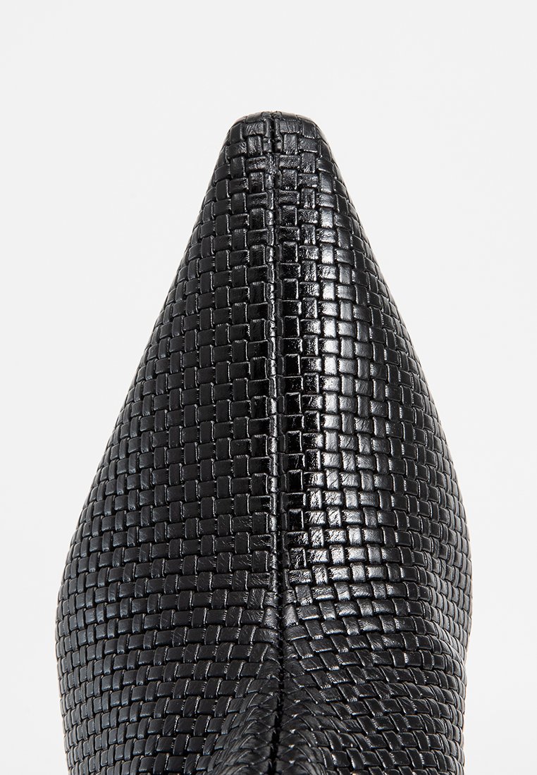 Schwarzer geflochtener Lederschuh mit spitzem Zeh und strukturiertem Obermaterial, ausgestattet mit einem glänzenden Finish und feiner Naht entlang der Naht.