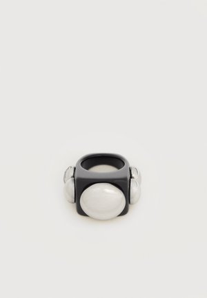 Zwart vierkant ring met vier grote afgeronde, parelachtige witte accenten aan elke zijde tegen een witte achtergrond.