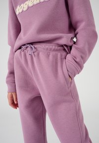 Set di felpa e pantaloni da jogging in lavanda realizzato in morbido tessuto. La felpa presenta un ricamo con la scritta "insieme"; i pantaloni da jogging hanno una vita con coulisse e tasche laterali.