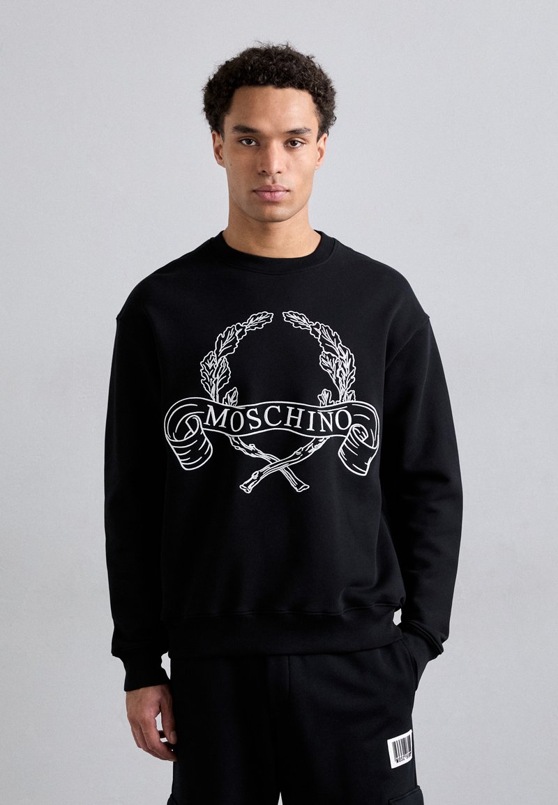 Fekete kapucnis pulóver fehér grafikával, amelyen a "MOSCHINO" felirat és egy babérkoszorú látható. Puha anyagból készült, klasszikus szabással.