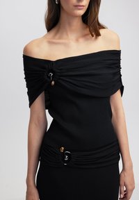 Zwart off-the-shoulder top van ribstof, met gathered details en ornamentele hardware-accenten bij de halslijn en taille.