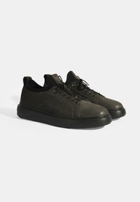 Donkergroene leren sneakers met een ronde neus, zwarte zool en vetersluiting. Beschikt over een textuurafwerking en minimalistische accenten.