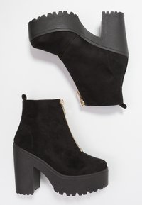 Mustat keinonahkakengät nilkkapituisella mallilla, joissa on paksu pohja ja korko. Kenkäparissa on sivuvetoketju ja sahahampainen kumipohja, joka tarjoaa pitoa.