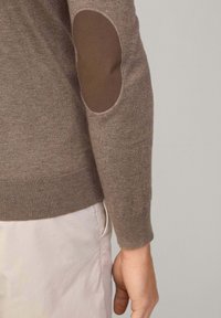 Brązowy sweter o dopasowanym kroju, z prążkowanymi mankietami i łatkami na łokciach z ciemniejszego brązowego materiału. Teksturowany dzianinowy materiał o gładkim wykończeniu.