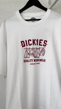 Bijela pamučna majica s kratkim rukavima, koja sadrži grafički otisak boje bordo s odjevnim predmetima i natpisom "Dickies Quality Workwear Since 1922."
