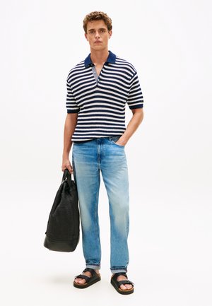 Prúžkované polo tričko s krátkym rukávom v námorníckej modrej a bielej, svetlomodré rifle, čierna taška s rukoväťami, čierne sandále, texturovaná pletená tkanina, voľný strih.