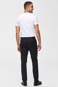 Čierne nohavice so slim fit strihom, textúrovaná tkanina a dve zadné vrecká. Skombinované s jednoduchým bielym tričkom s krátkym rukávom a čiernymi topánkami.
