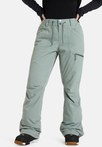 Lichtgroene sneeuwbroeken met een losse pasvorm, elastische tailleband, verstelbare trekkoord, zijzakken en een ritssluiting op de dijzak.