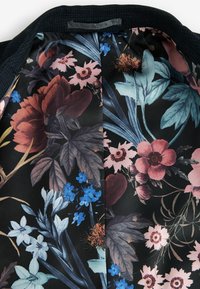 Blomster-mønsteret indvendigt med mørk baggrund; har roser, blade og forskellige blå blomster. Glat satin-tekstur.
