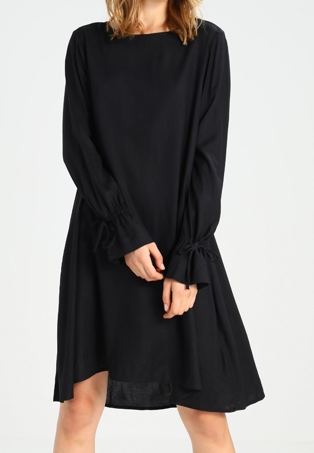 Robe noire à manches longues avec un décolleté carré et des détails froncés au niveau des poignets. Silhouette évasée, longueur genou, fabriquée à partir d'un tissu lisse.