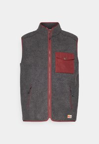 Fleece jopica v temno sivi barvi z rdečimi detajli, ki ima sprednji žep, dva stranska žepa in visok ovratnik. Mehka, teksturirana površina.