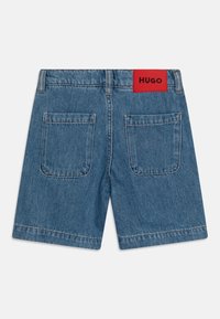 Μπλε τζιν σορτσάκια με κόκκινη ετικέτα λογότυπου στη μέση, διαθέτοντας δύο πίσω τσέπες και σχέδιο με ίσια γραμμή. Κλασική λεπτομέρεια ραφής.