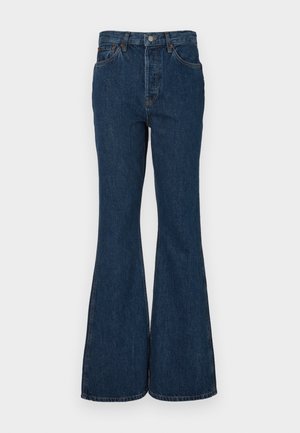 Ciemnoniebieskie dżinsy w stylu dzwonów, wykonane z denimu. Charakteryzują się wysokim stanem, pięcioma kieszeniami oraz kontrastowym przeszyciem. Gładka tekstura i staranne wykończenie.