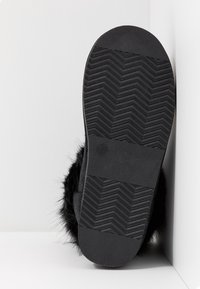 Pantofole nere con texture morbida, suola in gomma con motivo a zigzag e finitura liscia sulla punta con etichetta della taglia.