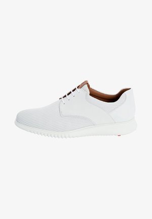 Baskets basses blanches en tissu texturé, doublure intérieure marron, fermeture à lacets à l'avant, et semelle blanche épaisse avec une accroche rainurée.