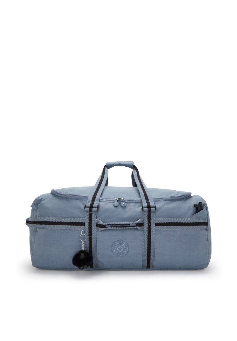 Pehmeä sininen duffel-laukku, jossa on mustat ja harmaat raidalliset kahvat, vetoketjullinen pääosasto, etutasku ja pieni musta pom-pom avaimenperä. 