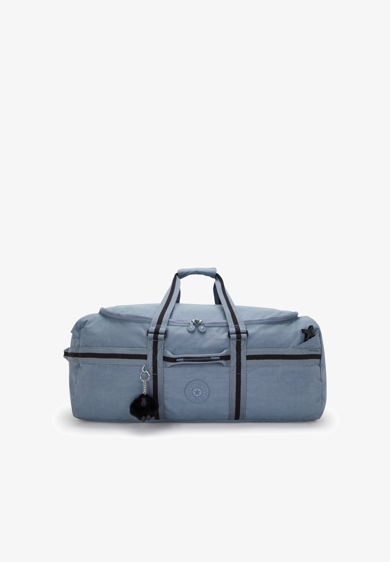 Pehmeä sininen duffel-laukku, jossa on mustat ja harmaat raidalliset kahvat, vetoketjullinen pääosasto, etutasku ja pieni musta pom-pom avaimenperä.
