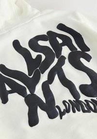 Sweat à capuche blanc avec un grand texte noir en gras disant "AVESALI NYTS LONDON" dans une police ondulée et déformée au dos.