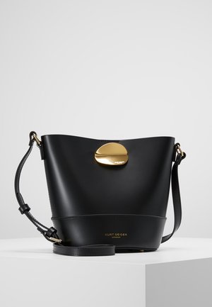 Zwarte leren bucketbag met verstelbare schouderriem en gouden ovale sluiting, met het merk "Kurt Geiger London" aan de voorkant.